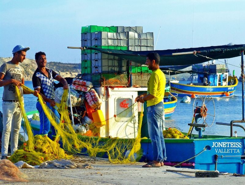Fishers with nets in a Maltese harbour